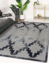 Load image into Gallery viewer, brown-and-teal-geometric-area-rug-in-modern-white-living-room-with-houseplant-and-gold-bar-cart